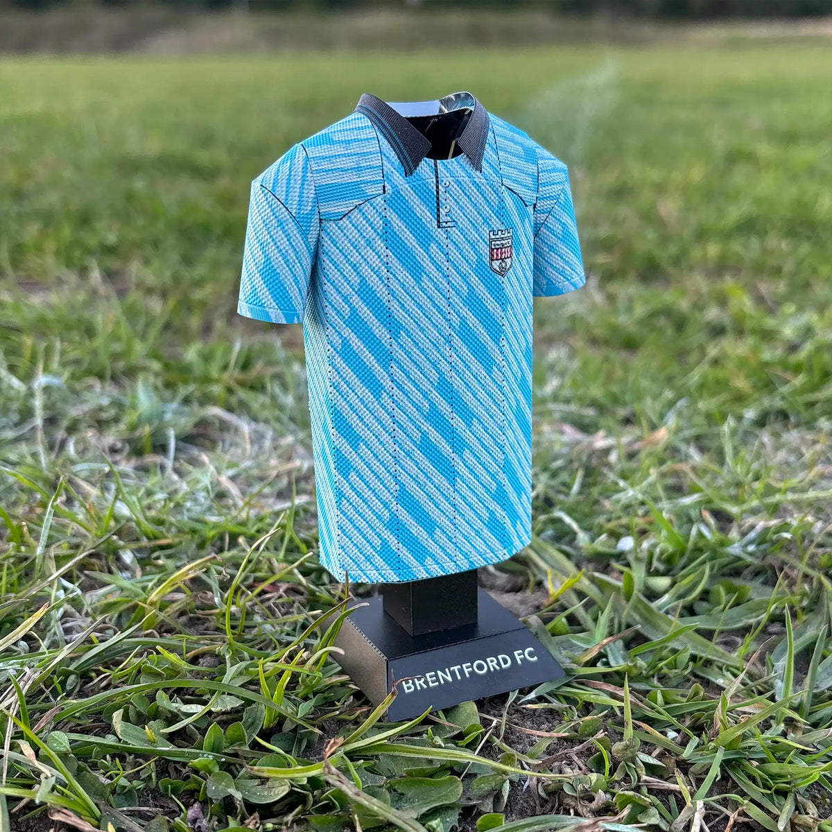 Square lifestyle product photograph of the retro light blue Brentford FC jersey collectible styled in a real-world setting.