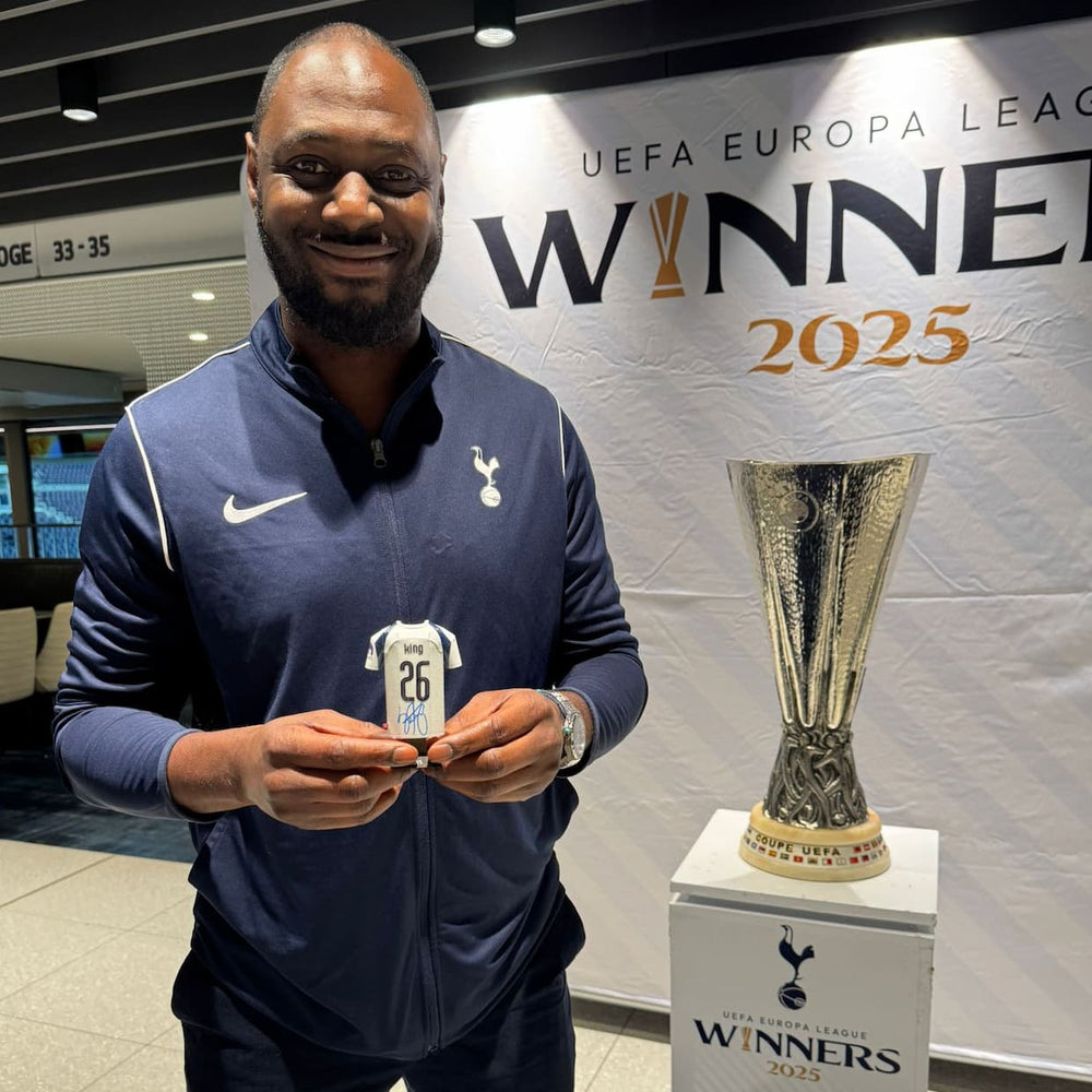 Man holding a sports jersey with a trophy and 'UEFA Europa League Winner 2025' banner in the background.