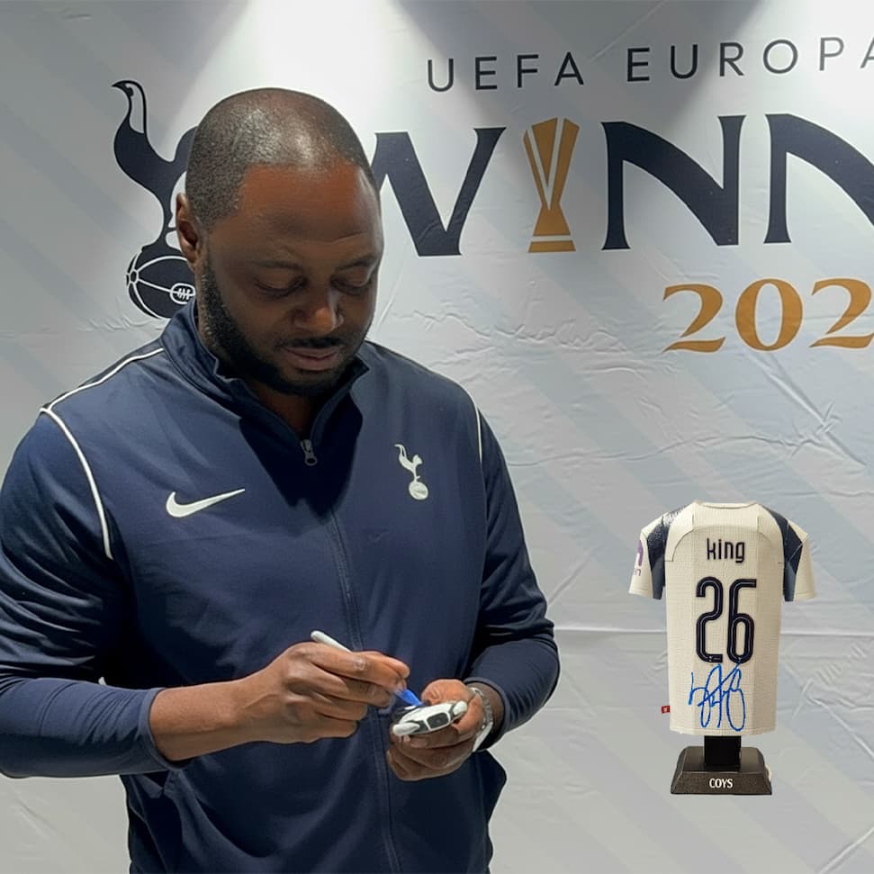 Man signing a sports jersey in front of a UEFA Europa League banner