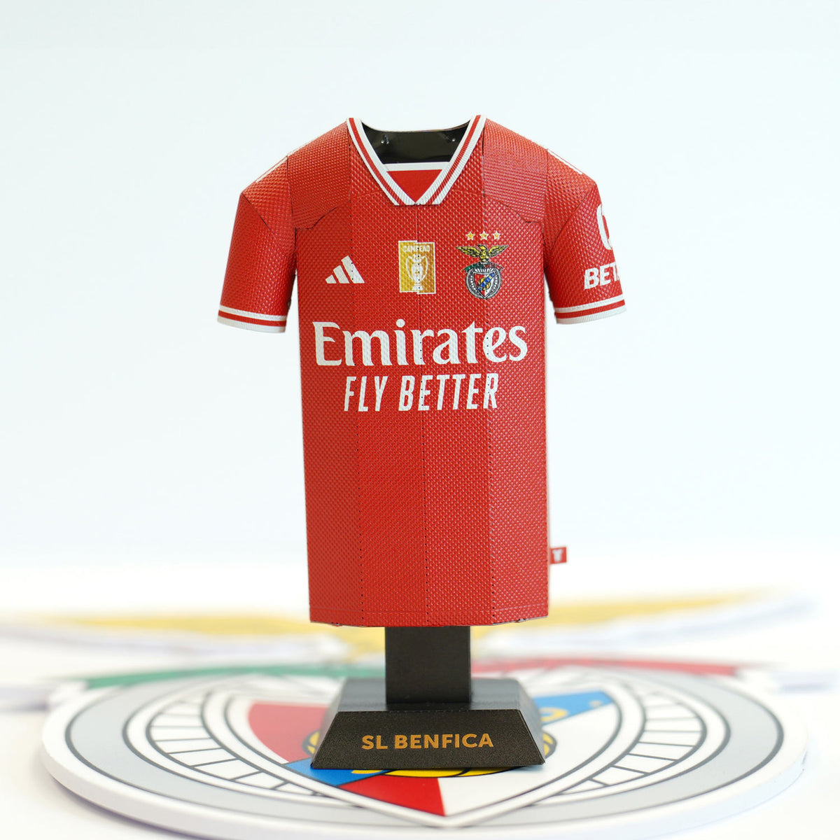 A detailed close-up view highlighting the front graphic design and crest of the red Benfica 2023/2024 home miniature jersey collectible