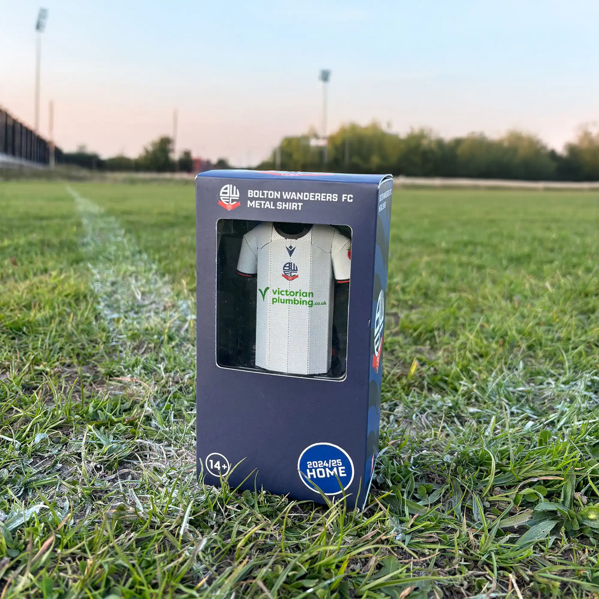 Square lifestyle product photograph showing the back view of a Bolton Wanderers FC jersey collectible displayed outdoors.