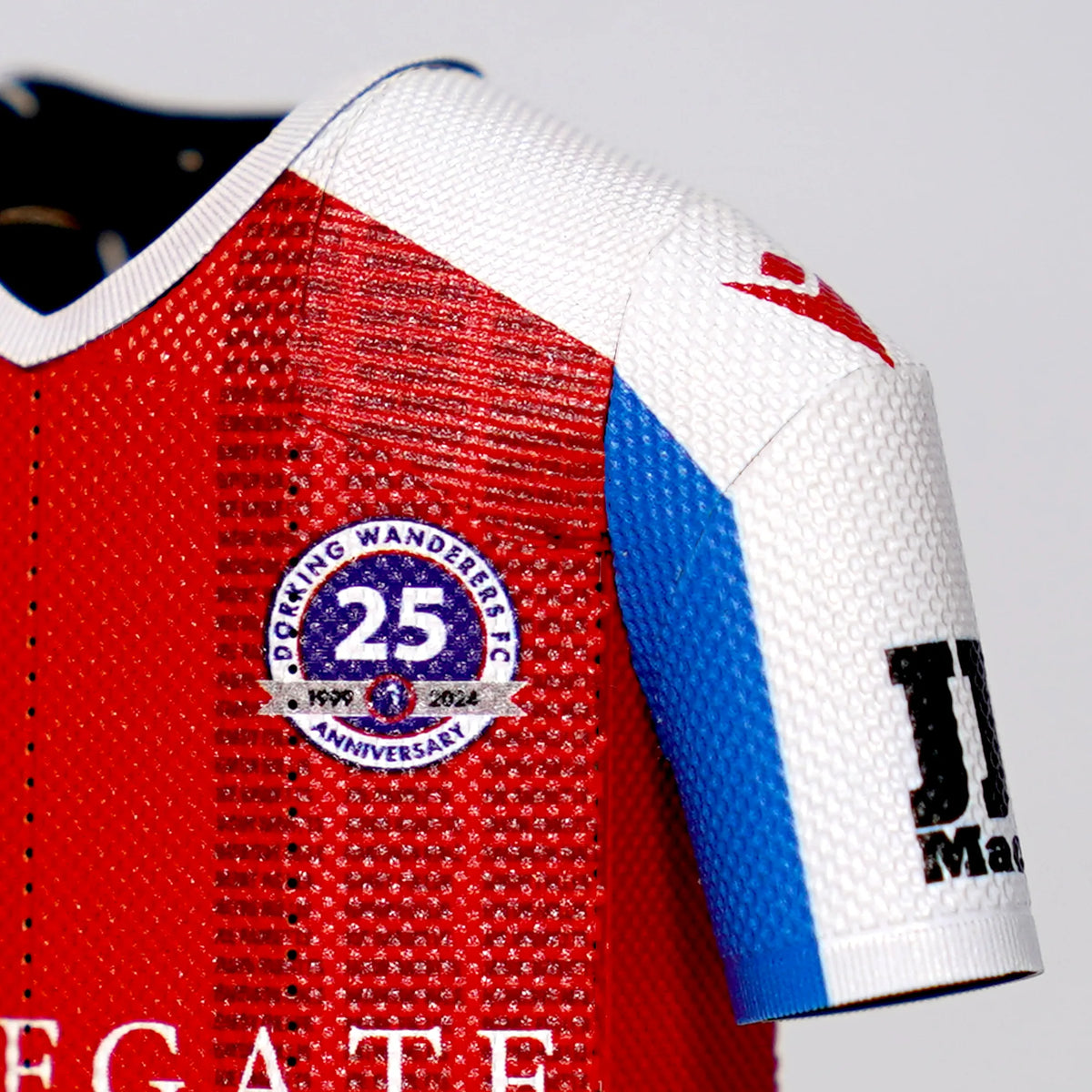 A close-up product photograph highlighting the 25-year anniversary commemorative crest detail on a Dorking Wanderers FC collectible jersey.